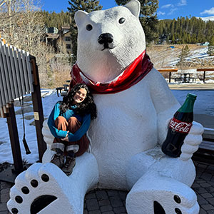 Picture of Riley Archuleta Sitting on a Coca Cola Bear Statue